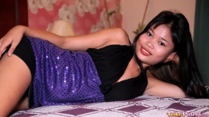 Sexy Asian teen posing in her dress while laying in bed