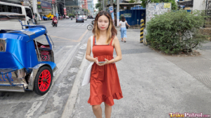 Filipina in a dress poses near trike in the Philippines
